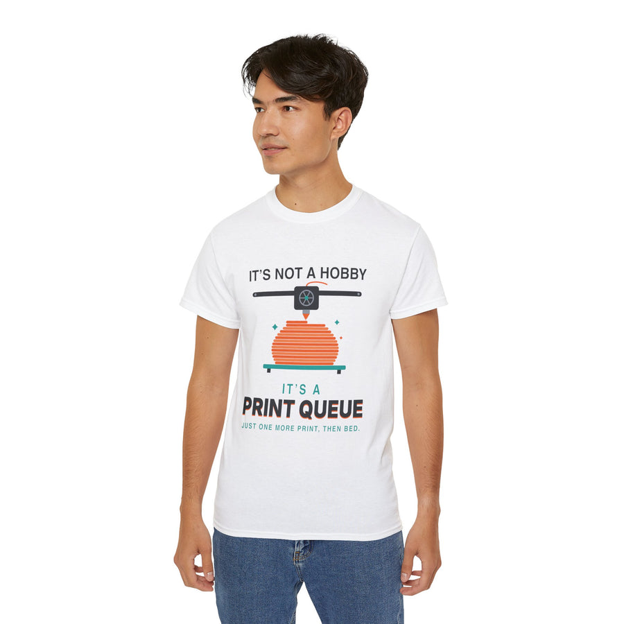 It's a Print Queue 3D printing graphic t-shirt by TeePara, folded and worn by a model
