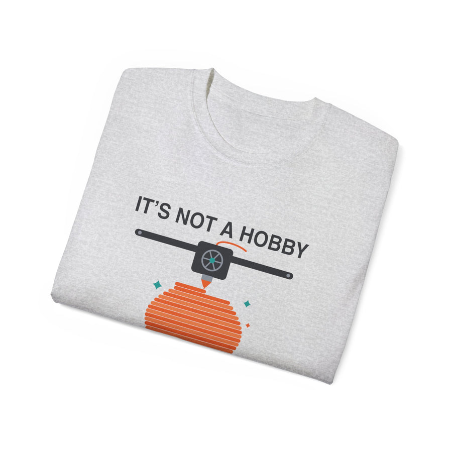 It's a Print Queue 3D printing graphic t-shirt by TeePara, folded and worn by a model