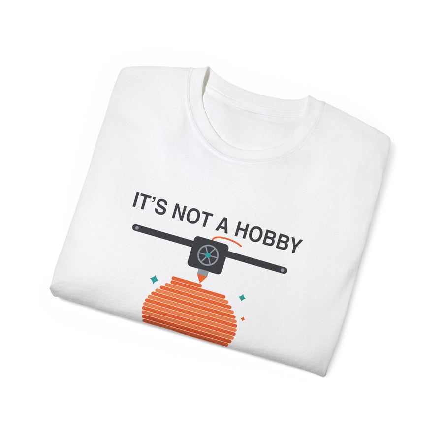 It's a Print Queue 3D printing graphic t-shirt by TeePara, folded and worn by a model