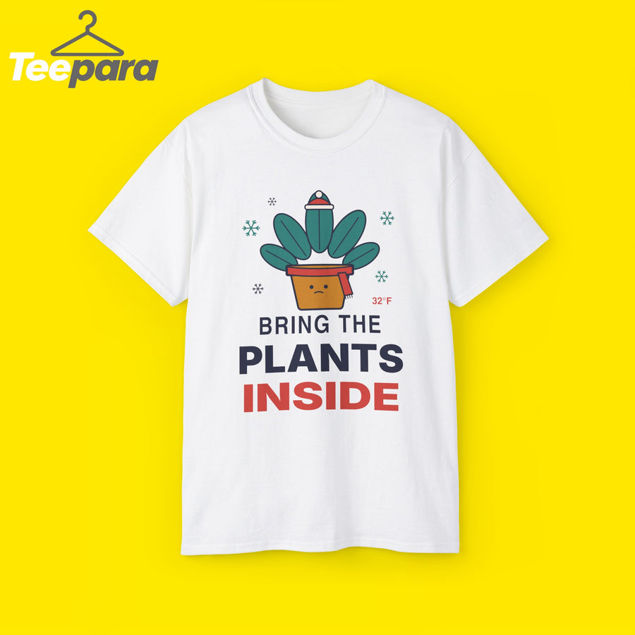 White unisex t-shirt with a potted plant wearing a beanie and scarf, snowflakes and the text Bring The Plants Inside