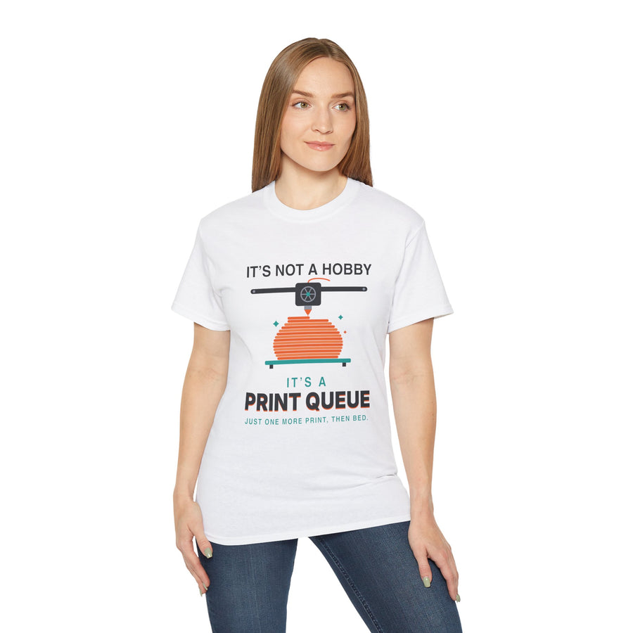 It's a Print Queue 3D printing graphic t-shirt by TeePara, folded and worn by a model